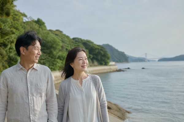 今治の海辺としまなみ海道を背景に散歩する日本人の大人の男女